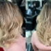 Back view of blonde balayage on medium-length hair with soft waves and natural gradient color in a San Antonio hair salon
