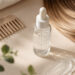 Hair care serum, comb, and highlighted hair on a neutral surface