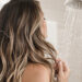 Woman with long highlighted hair in a shower, illustrating hard water hair damage in San Antonio. Copiar alt text